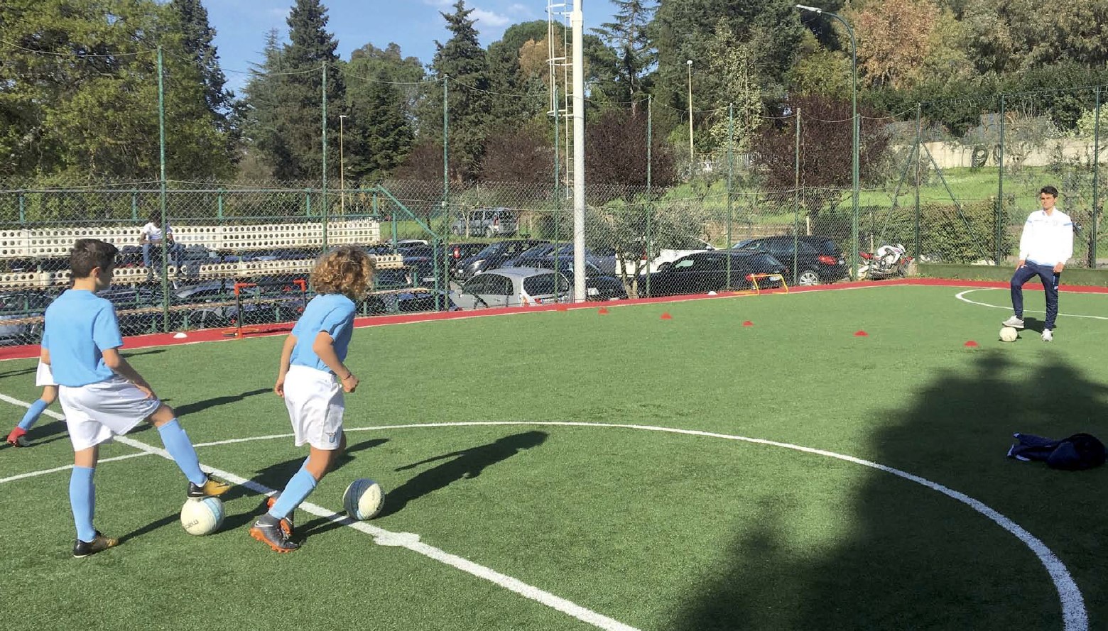 Primo piano delle gambe del giocatore di calcio bambino che calcia la  palla. Kid running classico pallone da calcio bianco e nero. Bambini della  scuola sul campo da gioco di calcio. Pratica